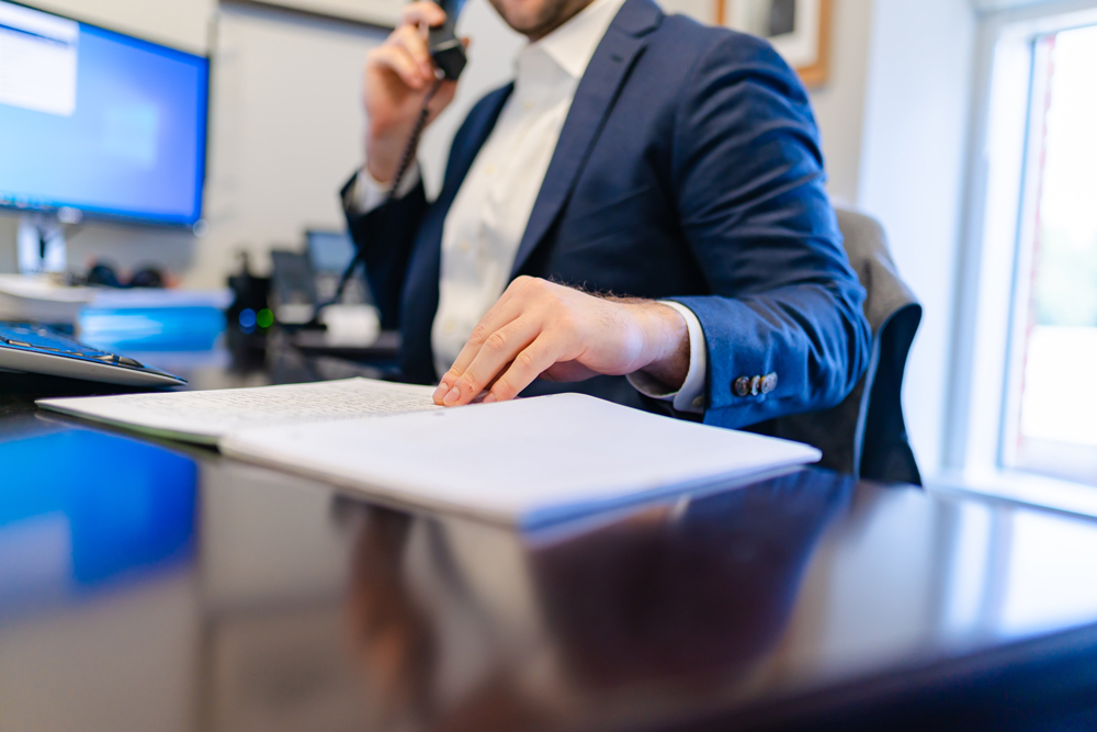 An image of a male medical billing expert witness sitting at a desk on the phone with a pad of paper in front of him. About Veritas Experts page